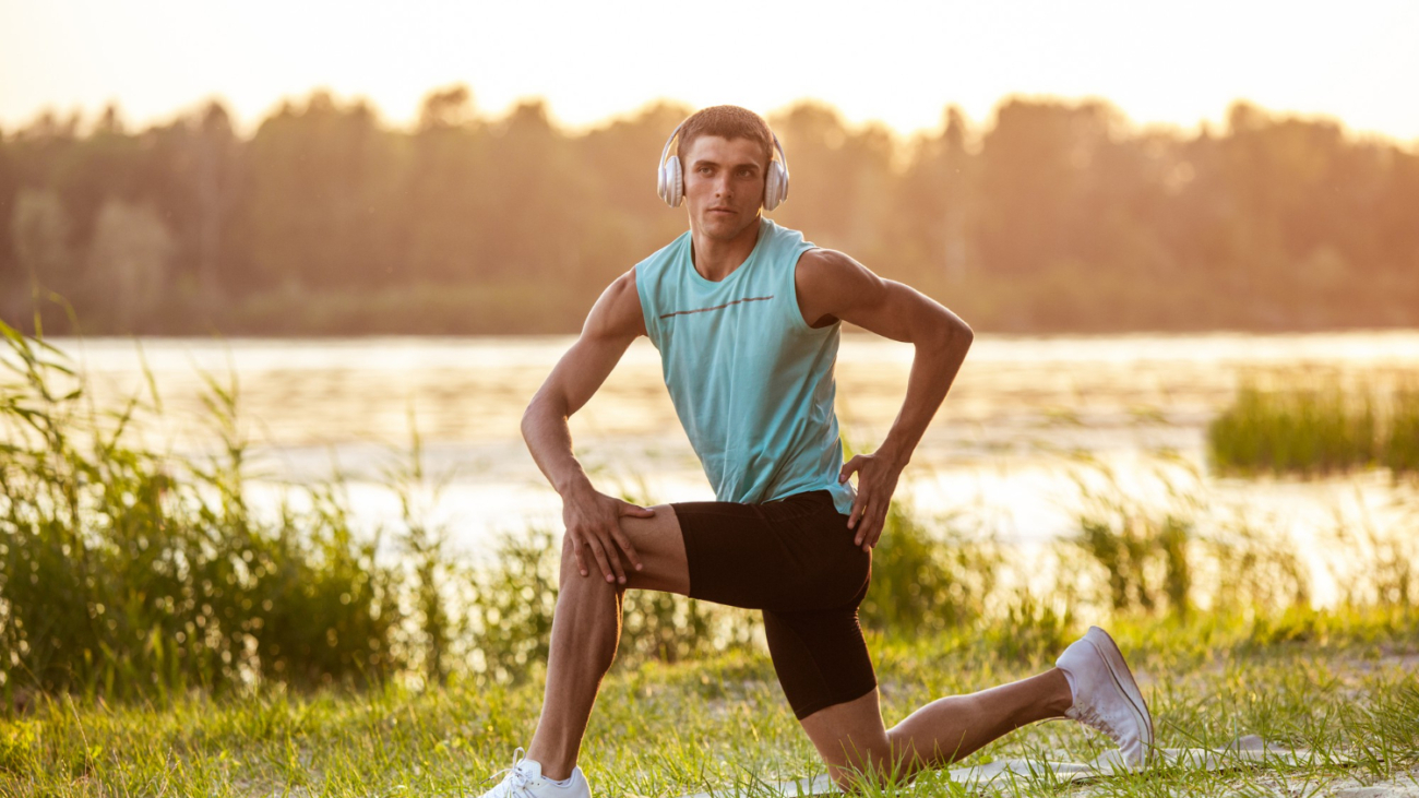 young-athletic-man-working-out-listening-music-riverside-outdoors