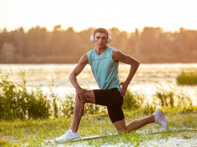 young-athletic-man-working-out-listening-music-riverside-outdoors